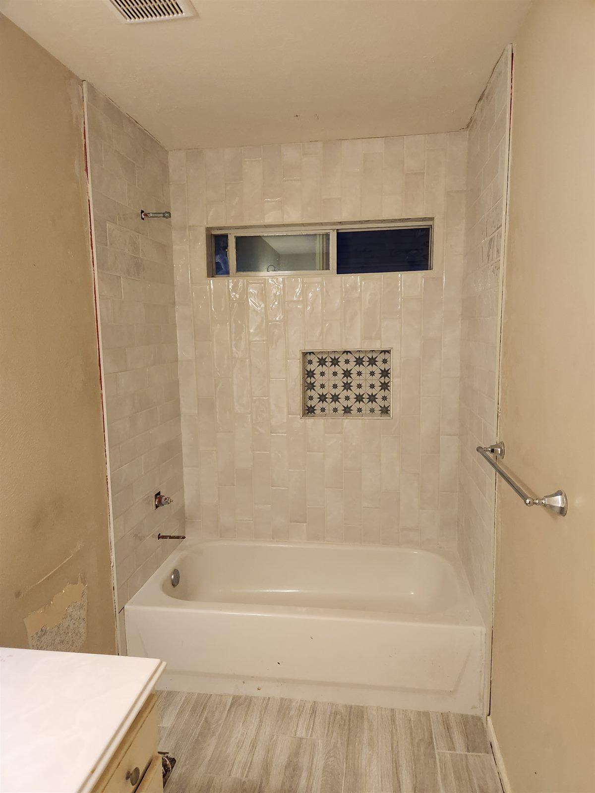 Finished bathroom with a soaking tub and tiled shower surround with recessed niche