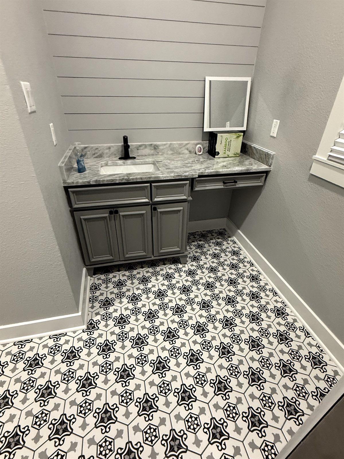 Bathroom vanity with a stone countertop over a patterned black-and-white tile floor
