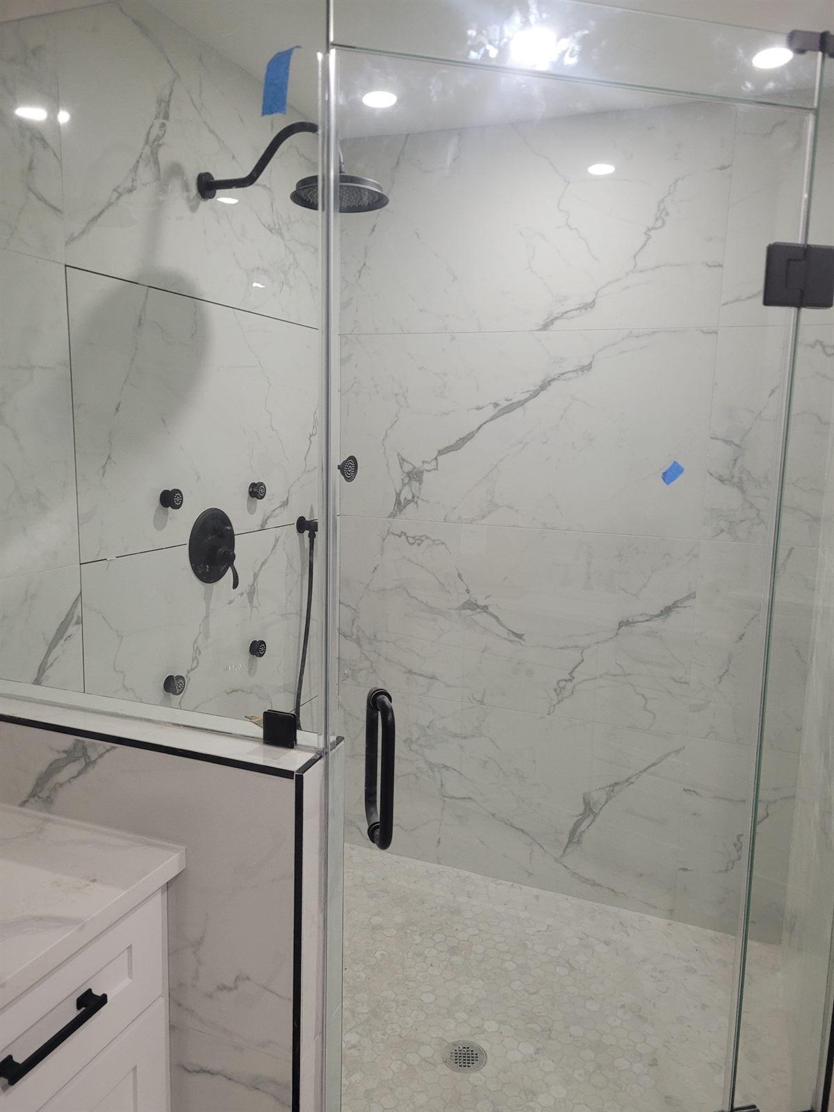 Spacious walk-in tile shower with a pebble stone floor and matte black fixtures
